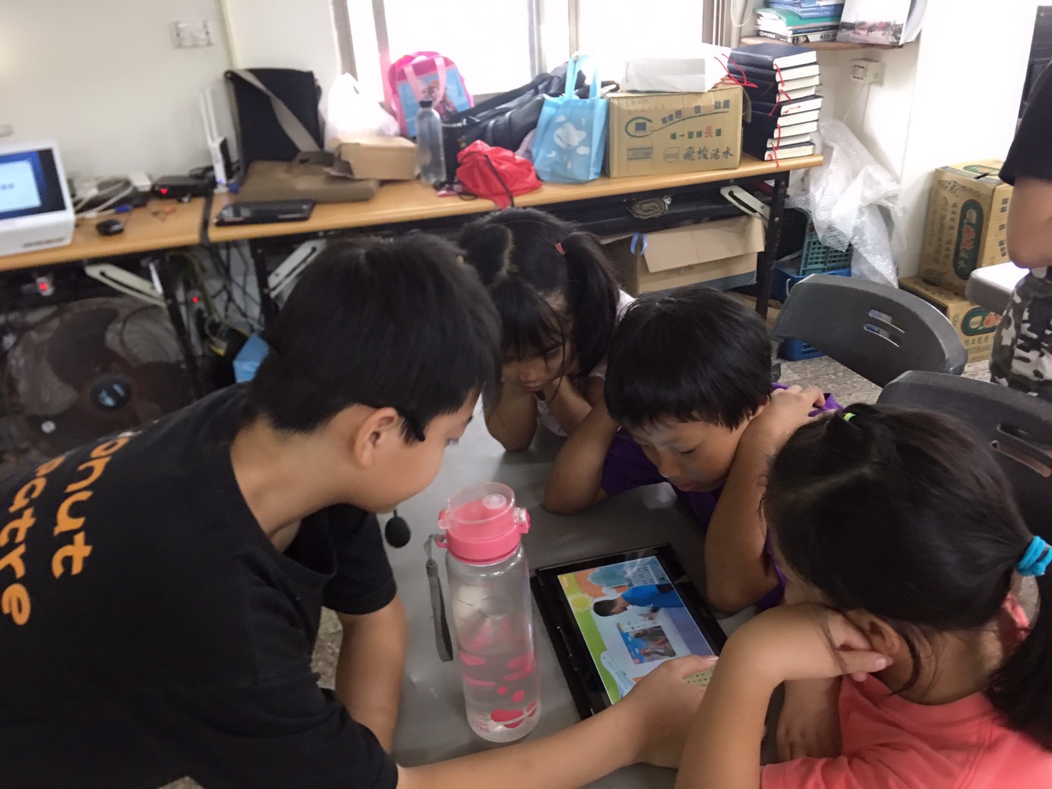 講師拿出平板電腦以APP跟孩子們互動
