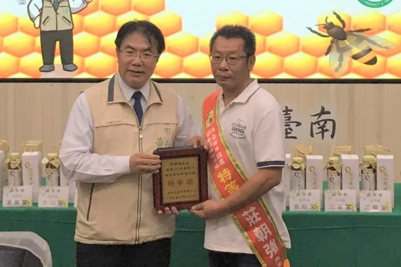 台南市國產蜂蜜評鑑比賽勇奪第一名的莊朝強（右），投入養蜂才3年，第一次參賽就一舉奪冠，市長黃偉哲（左）頒獎。圖／莊朝強提供